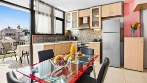 A modern kitchen with wooden cabinets, a glass dining table, and a refrigerator. - Emmanouel Maisonette Near the Sea (Chania)