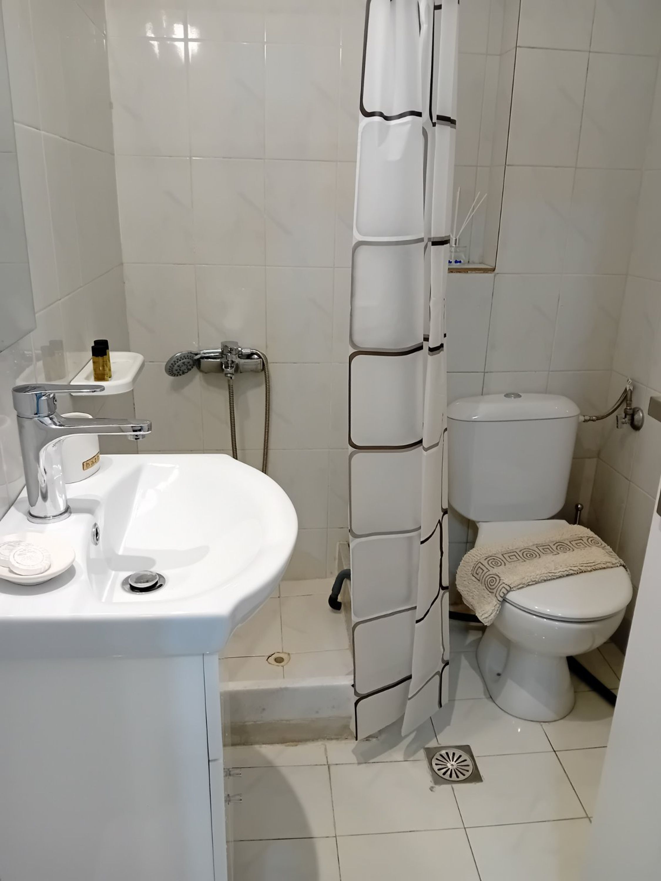 A bathroom with a white sink, toilet, and shower curtain.