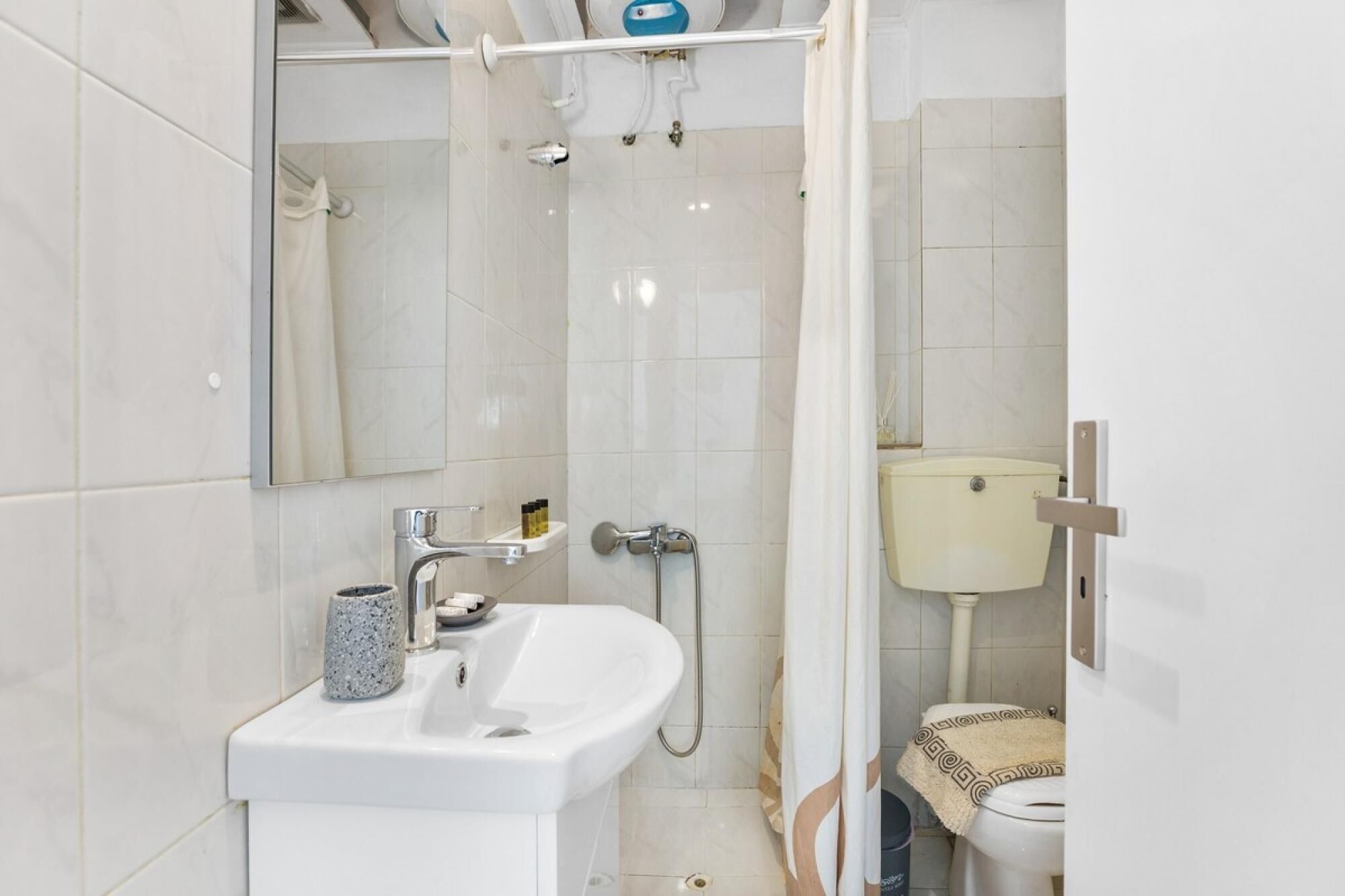 Une salle de bain moderne avec un lavabo blanc, un miroir et un espace douche.
