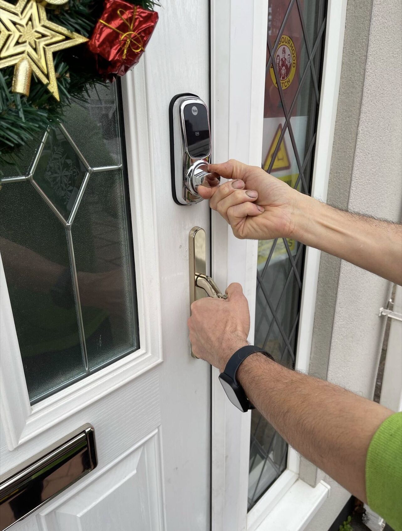 A person unlocking a white door with a Yale deadbolt lock.