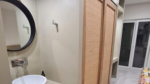 Un baño moderno con un espejo redondo, un lavabo blanco y un separador de madera.