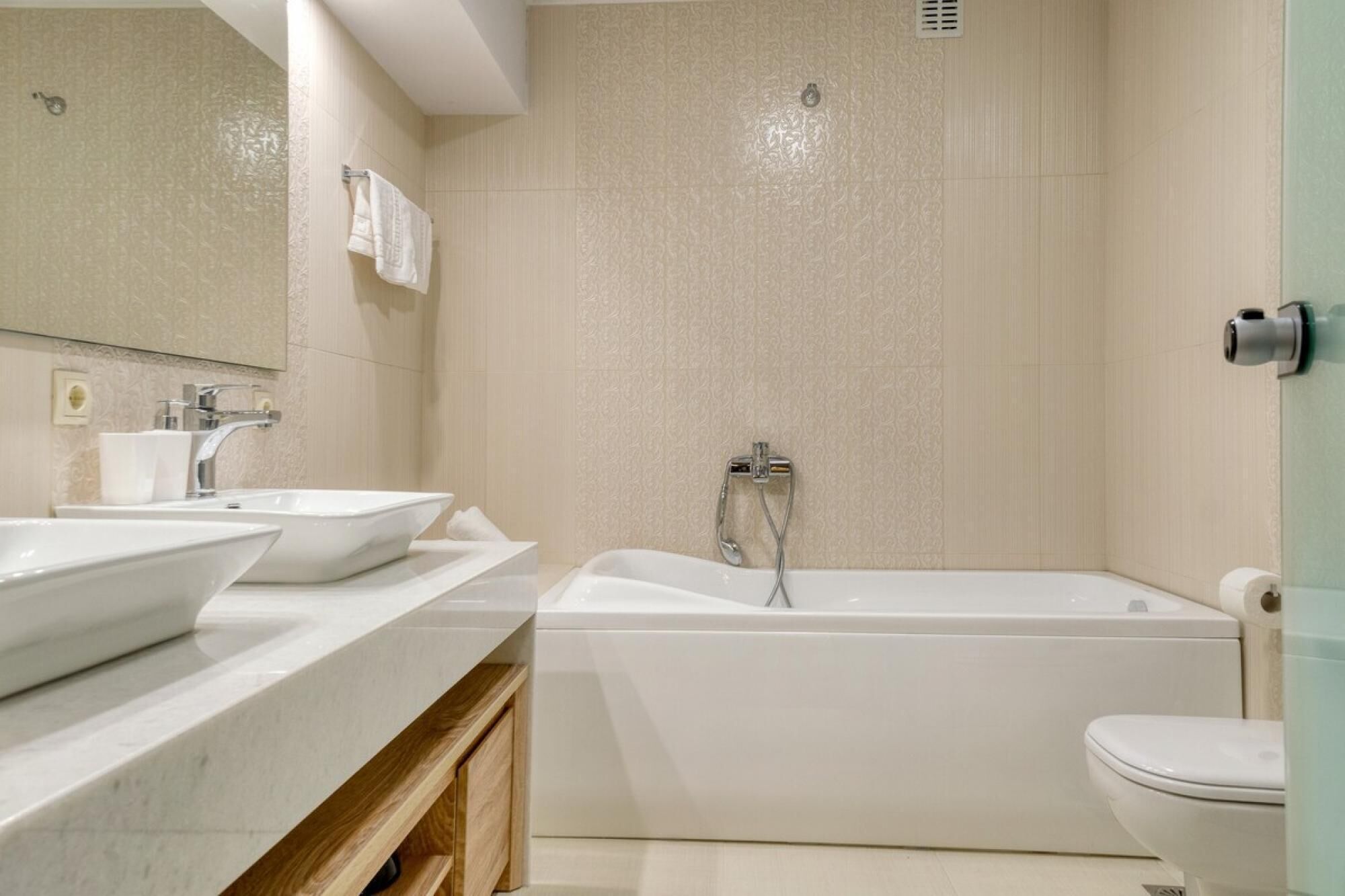 Un baño moderno con dos lavamanos, una bañera y un inodoro.