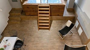 Une pièce au plancher de bois, équipée d’un jacuzzi, d’une échelle et de deux fauteuils de relaxation.