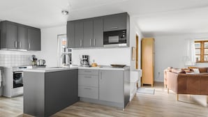 Una cocina moderna con gabinetes grises, microondas integrado y cafetera.