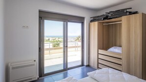 A bedroom with a sliding glass door to a balcony, a bed with white bedding, and a wooden wardrobe. - Kayzo Luxury Apartment With Pool (Platanias)