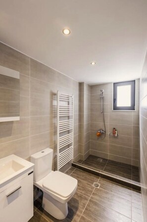 A modern bathroom with a toilet, sink, and shower.