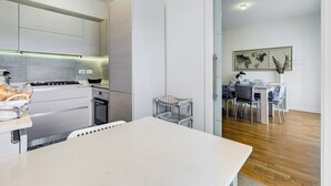 A modern kitchen with built-in appliances, a dining area with a table and chairs, and a view of the living room. - Valle Aurelia vatican apartment: Your Charming Retreat bear S.Peter (Roma)
