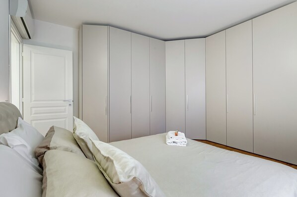 A bedroom with a bed, pillows, a folded towel, and a wardrobe.