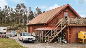 A wooden cabin with a metal roof, a staircase, and a small porch.