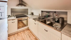 A modern kitchen with stainless steel appliances, wooden flooring, and a built-in oven.