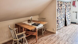 A cozy dining area with a wooden table and chairs, a small vase with flowers, and a book.