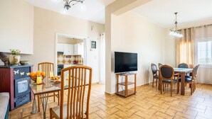 A spacious living area with a kitchen, dining table, and TV. - Ortansia House Near the Sea (Platanias)