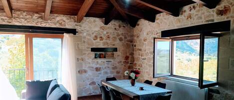 Un intérieur rustique en pierre avec une table à manger, des chaises et un canapé.