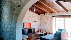 A stone-walled living room with a wooden ceiling, a flat-screen TV, and a sofa. - Traditional Villa in Pemonia (Apokoronas)