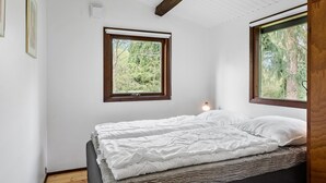 Un dormitorio con cama, dos ventanas y un ventilador de techo.