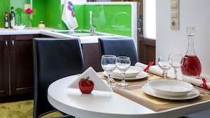 Un coin repas avec une table blanche dressée pour deux personnes, comprenant des assiettes, des verres et une pomme rouge.