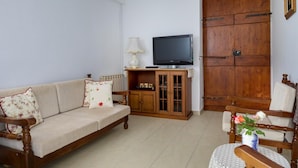 Un salon avec un canapé, un meuble en bois, une télévision et un fauteuil.