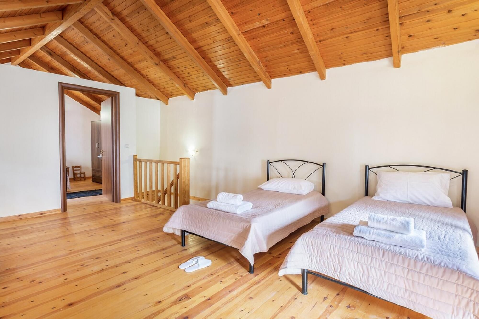 Ein Zimmer mit zwei Betten, Holzboden und schrägverdeckter Decke.