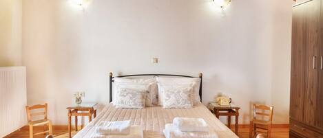 A bedroom with a bed, two bedside tables, a wooden wardrobe, and a wooden ceiling.