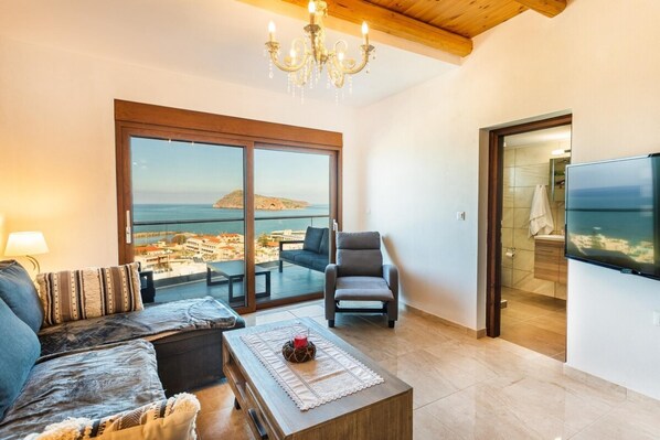 Un vaste salon doté d’une grande porte-fenêtre coulissante donnant sur un balcon avec vue sur la mer.