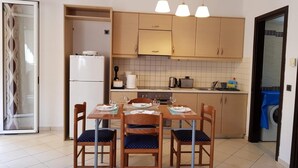 A compact kitchen with a dining area, including a refrigerator, stove, and various kitchen appliances. - Ilia s Apt in Chania (Chania)