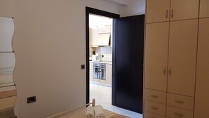 A bedroom with a bed, a wardrobe, and a bathroom visible through an open door. - Ilia s Apt in Chania (Chania)