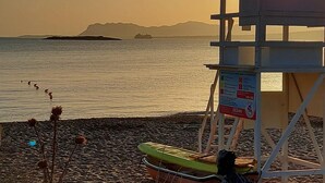 A lifeguard tower with a flag, a green rescue boat, and a sign indicating 'OCEAN' and 'RESCUE & FIRE'. - Chrissoula House In Agioi Apostoloi (Chania)