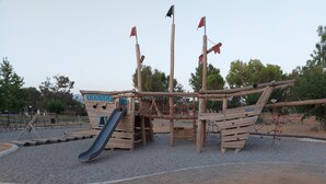 A wooden pirate ship play structure with a slide and climbing net. - Chrissoula House In Agioi Apostoloi (Chania)