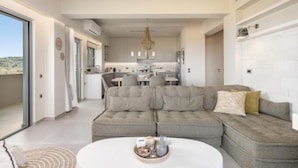Una sala de estar moderna con un sofá modular, una mesa de centro redonda y vistas a la cocina y el comedor.