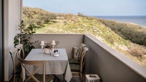 Un balcón con una mesa lista para dos personas, con vistas a un paisaje costero.
