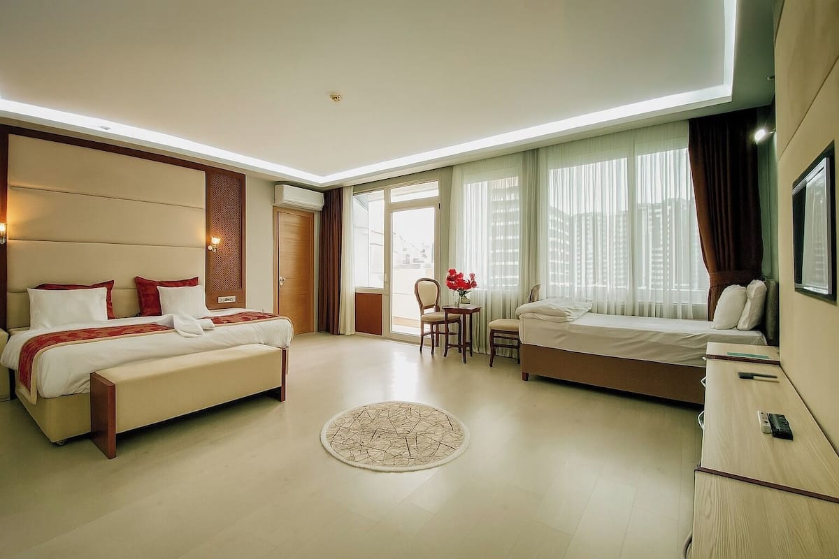 A modern hotel room with a large bed, a smaller bed, a desk, and a chair.