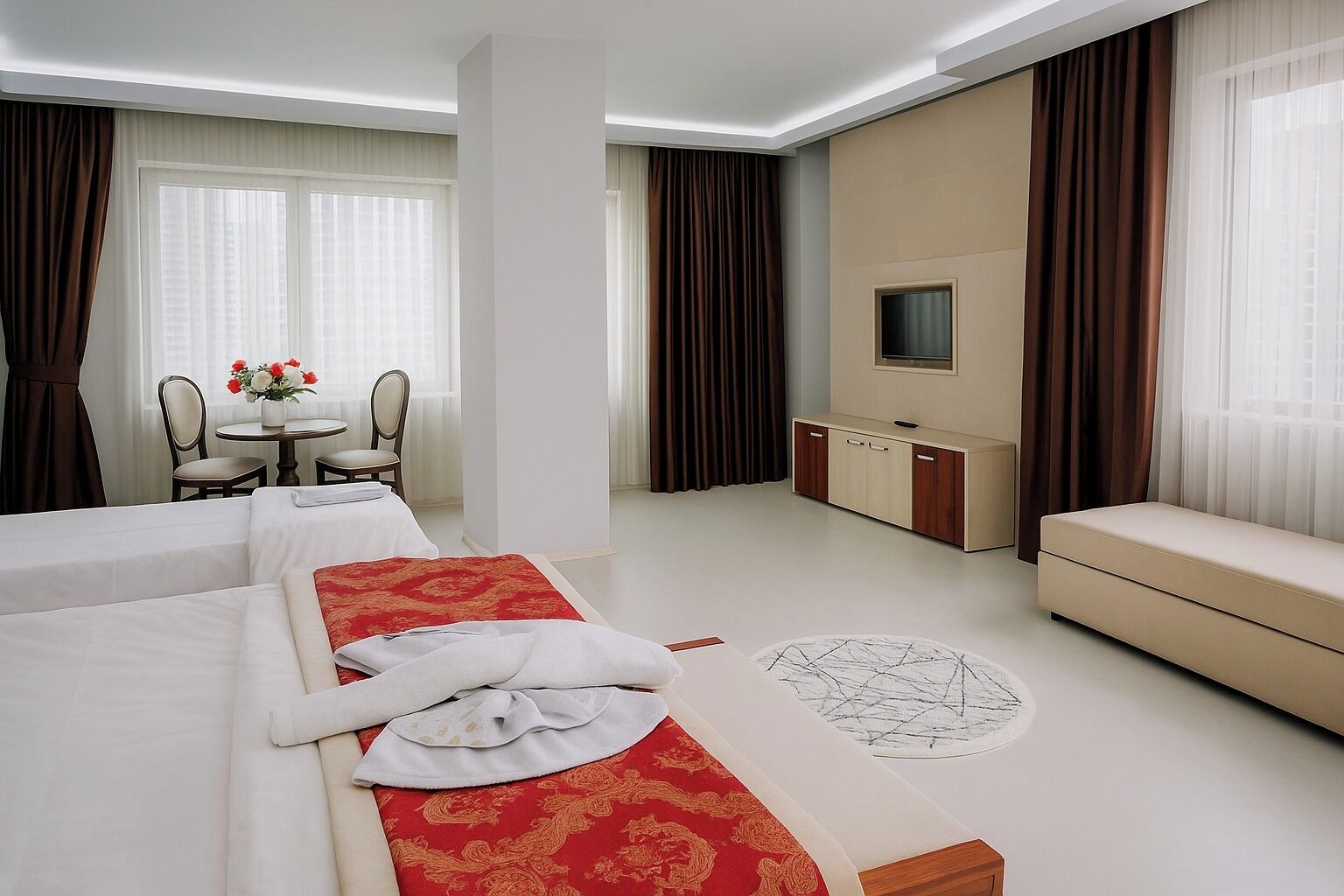 A hotel room with two beds, a sofa, a dining area, and a TV.