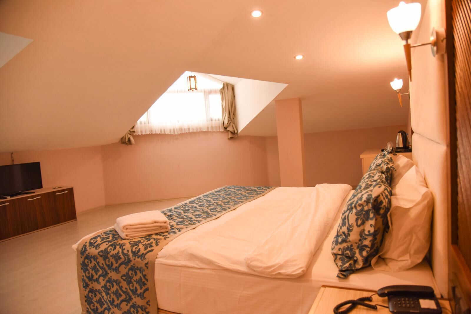 A bedroom with a bed, a TV, a desk, and a telephone.