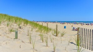 A beach with sand dunes, a wooden fence, and beachgoers. - Ocean Princess-Beautiful 2 Bedroom Condo! (Ocean City)