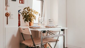 A compact dining area with a white table, a potted plant, a wine glass, and a sign indicating an exclusive location. - Studio S. José By Gt House (Lisbon)