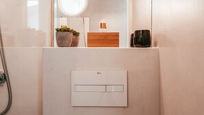 A bathroom with a shower, a mirror, a sink with a wooden countertop, and a potted plant. - Studio S. José By Gt House (Lisbon)