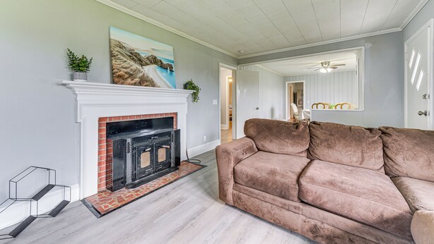 Un salon avec une cheminée, un canapé marron et un ventilateur de plafond.