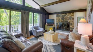 Una sala de estar acogedora con chimenea de piedra, sofás de cuero y un televisor.