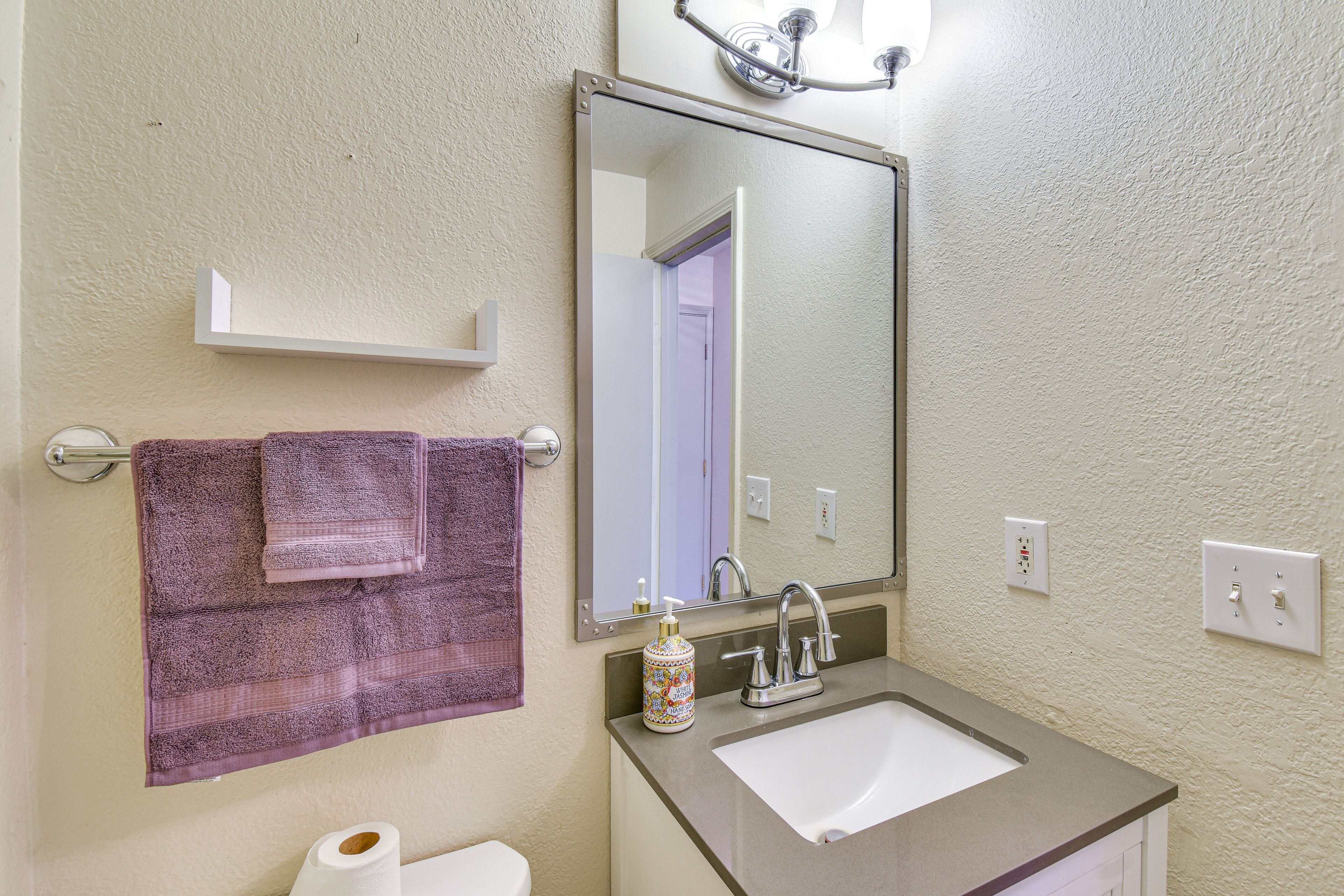 A bathroom with a sink, mirror, towel rack, and toilet.