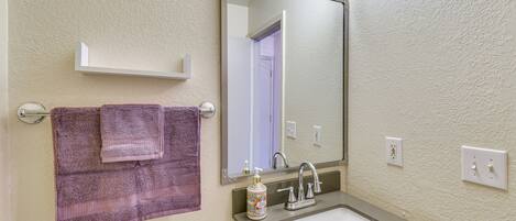 A bathroom with a sink, mirror, towel rack, and toilet.