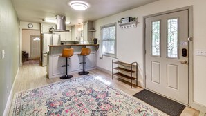 A kitchen with a refrigerator, stove, and two bar stools. There is a window with a view of trees and a door with a coat rack. - Lake Access & Hot Tub: Pet-friendly Arnold Home (Arnold)