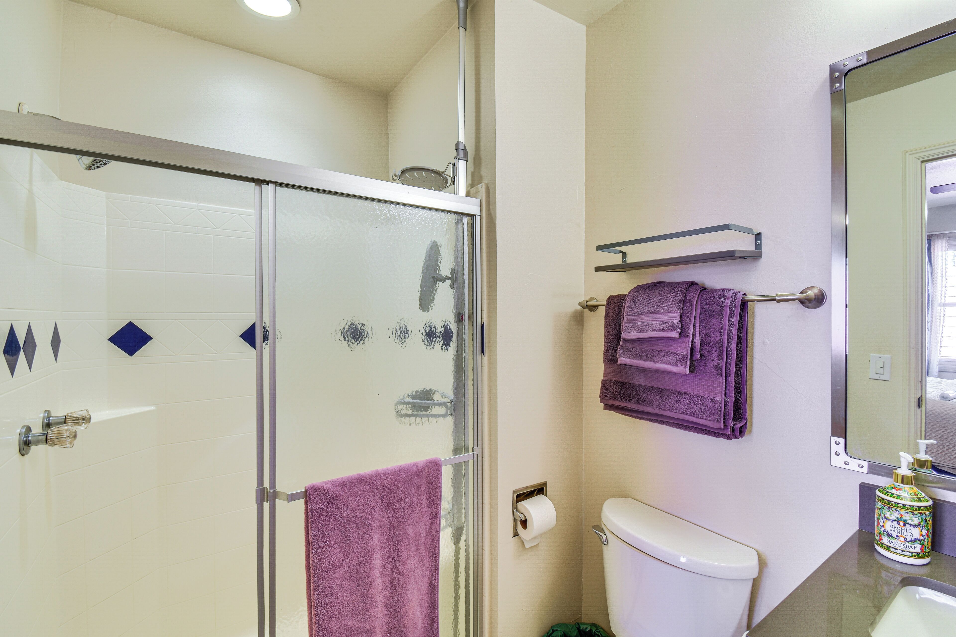Une salle de bain avec une douche à parois de verre, des toilettes, un lavabo et un miroir.