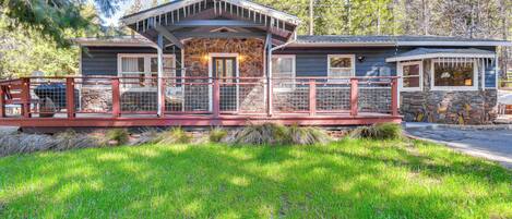 A lodge with a stone exterior, a covered porch, and a fenced deck area.