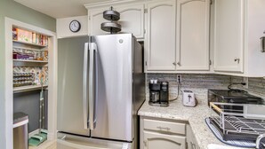 A kitchen with white cabinets, a stainless steel refrigerator, a coffee maker, a toaster, and a dish rack. - Lake Access & Hot Tub: Pet-friendly Arnold Home (Arnold)