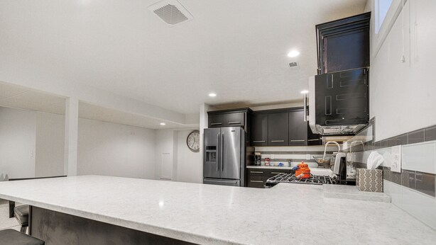 A modern kitchen with a large island, stainless steel appliances, and dark cabinetry.