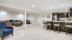A modern kitchen with a bar area, a dining set, and a living area with a sofa and chairs.