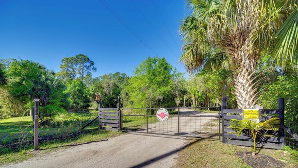 A gated entrance to a property with a no trespassing sign, surrounded by lush greenery and trees.
