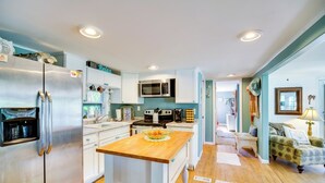 A modern kitchen with stainless steel appliances, a wooden island, and a dining area with a vintage sofa.