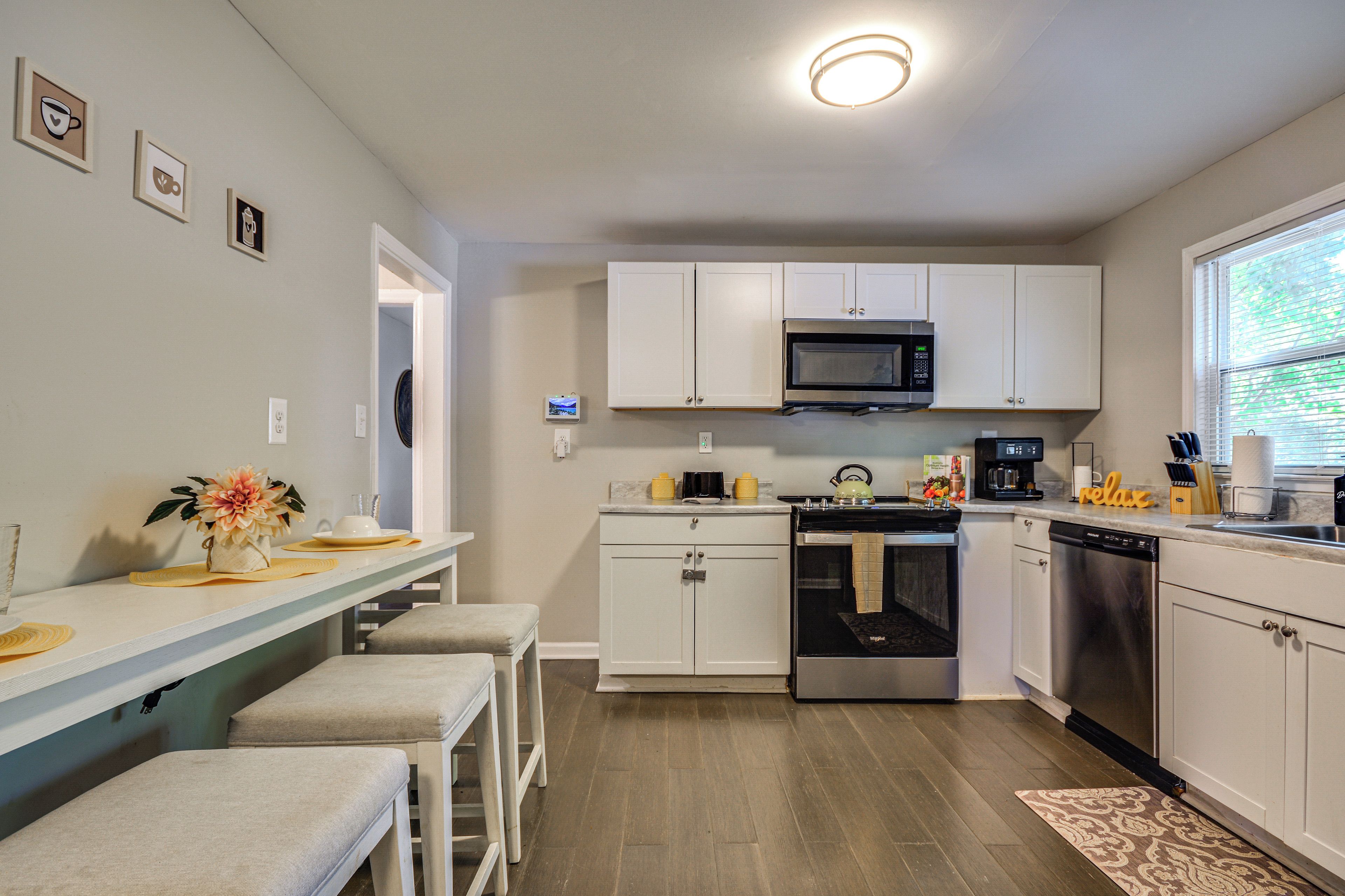 A modern kitchen with white cabinets, stainless steel appliances, and a bar area with stools.