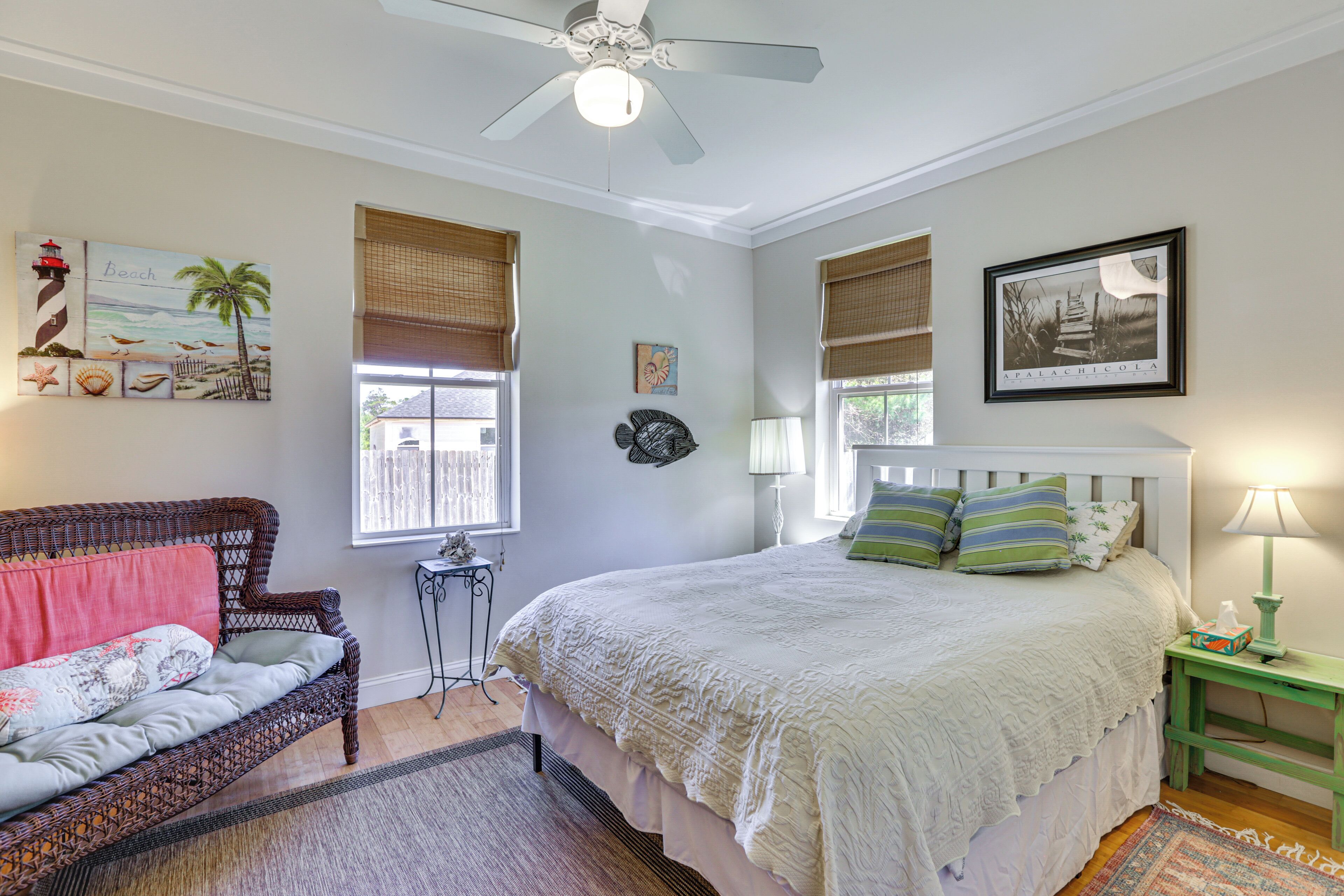A bedroom with a bed, a sofa, a ceiling fan, and a window with blinds.